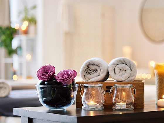 Bloom Spa dinlenme alanında katlanmış havlular, mumlar ve çiçek düzenlemesi